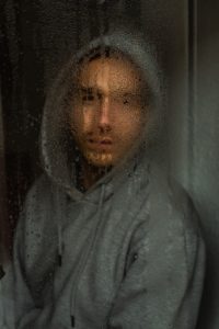 Man staring out of rainy window